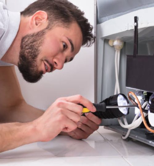 Photo Of Male Technician Repairing Refrigerator With Screwdriver